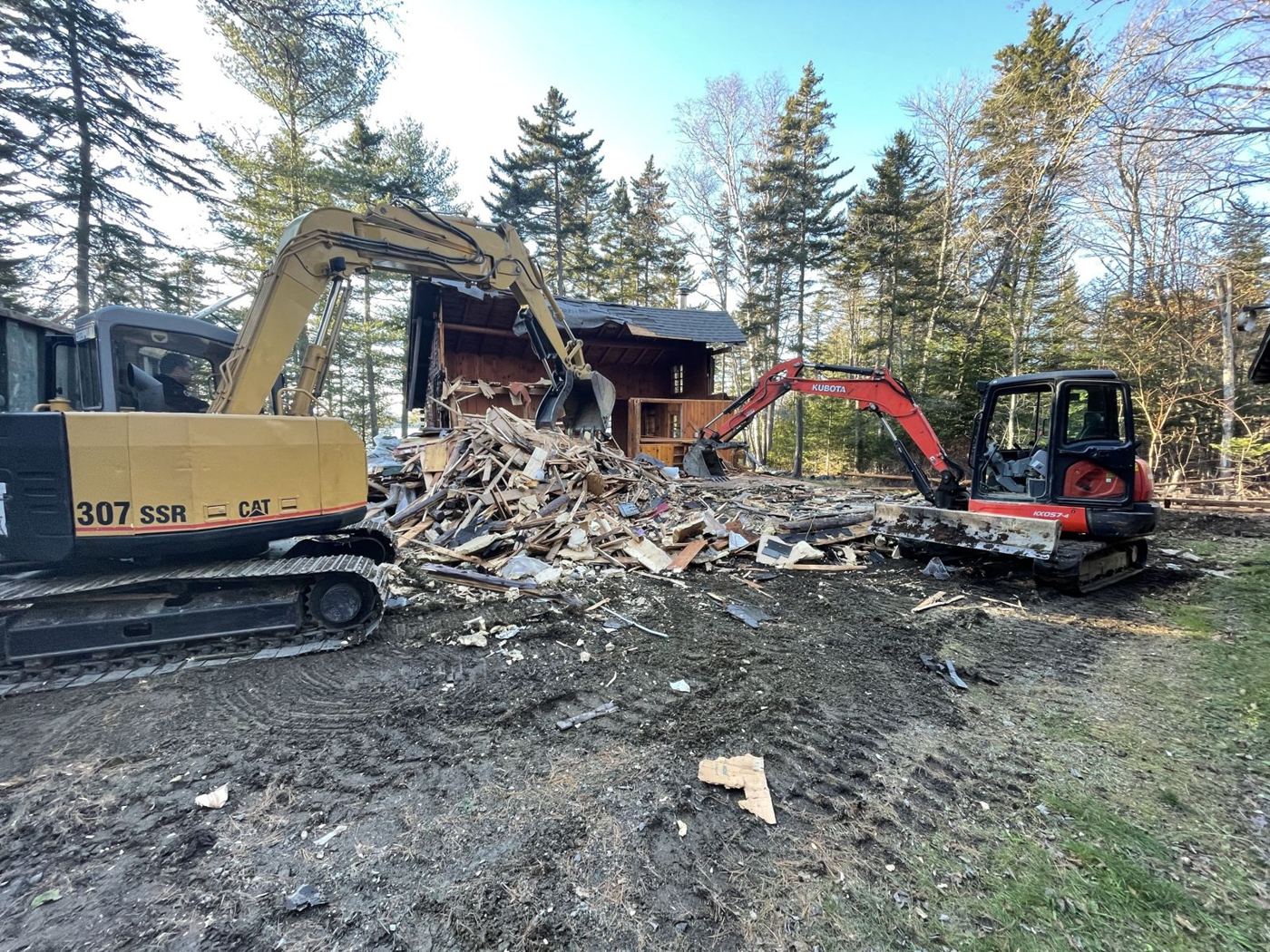 Two excavators taking down the old log cabin