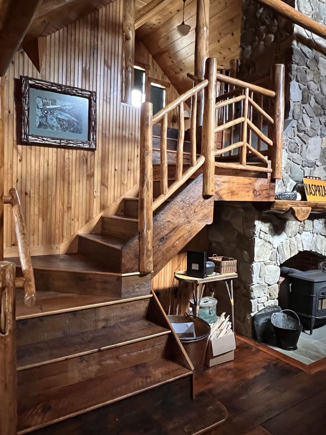 Camp interior with a log stair, pine walls and stone hearth