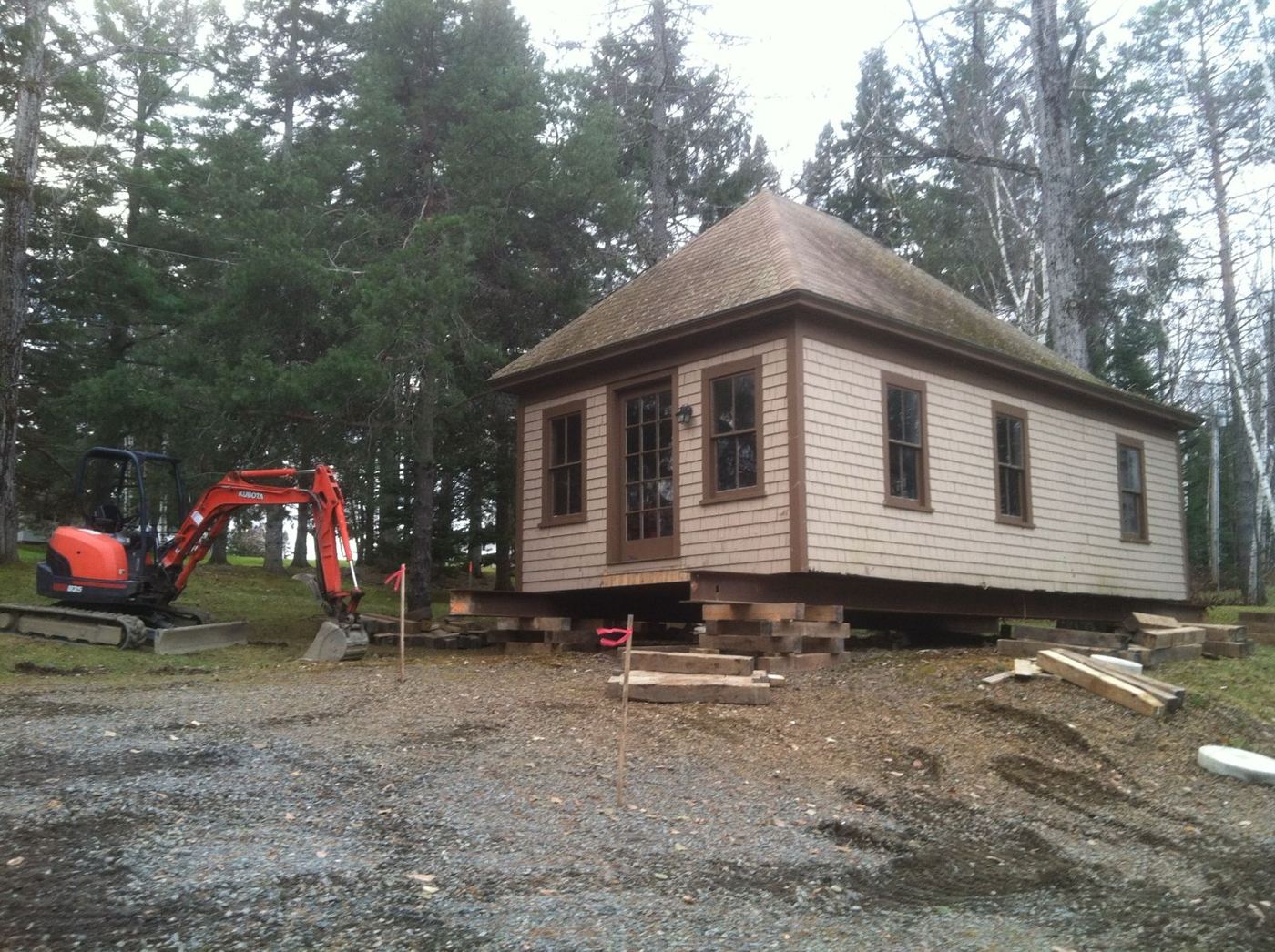Shingled camp jacked up on steel beams and cribbing