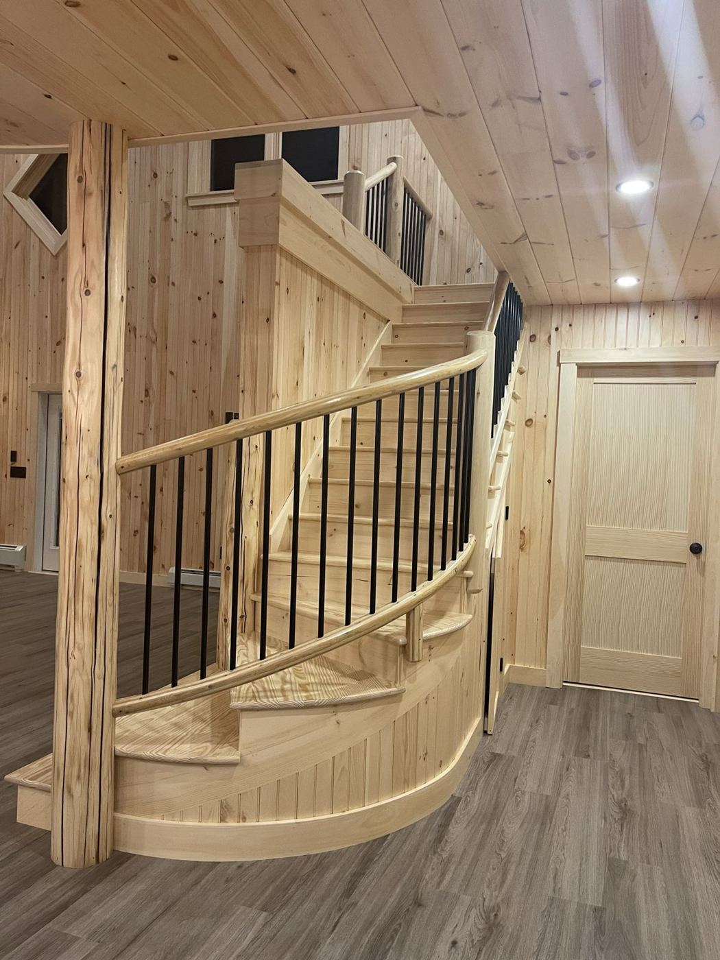 Curved pine staircase with log handrail and black balusters