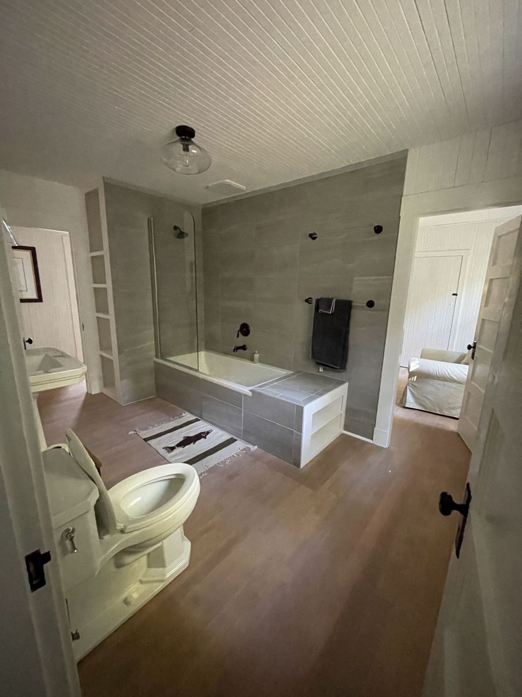 Bathroom with a gray-tiled tub surround, glass panel and built-in shelves