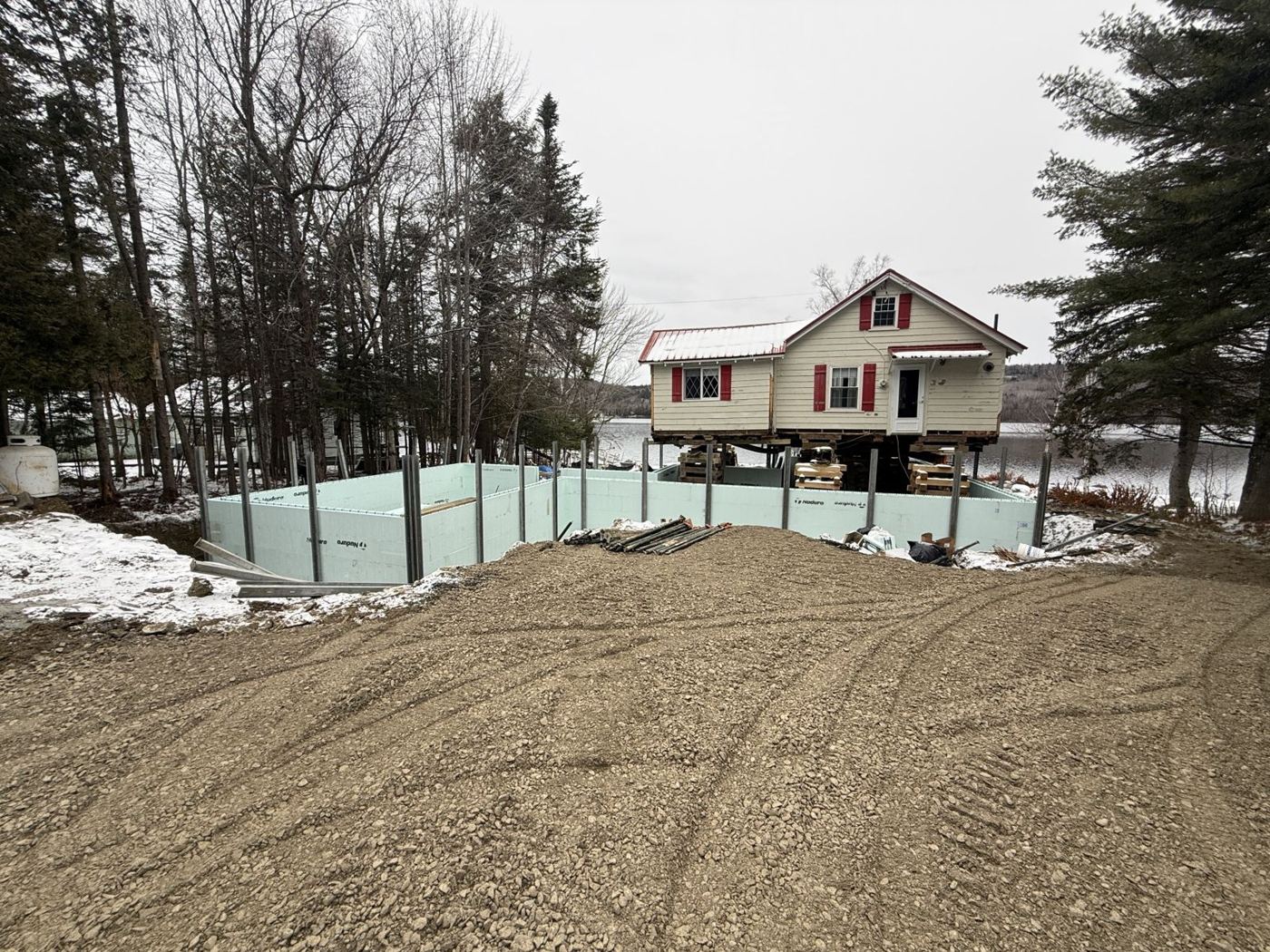 ICF foundation walls braced and ready, with the lifted camp beside it on the lake