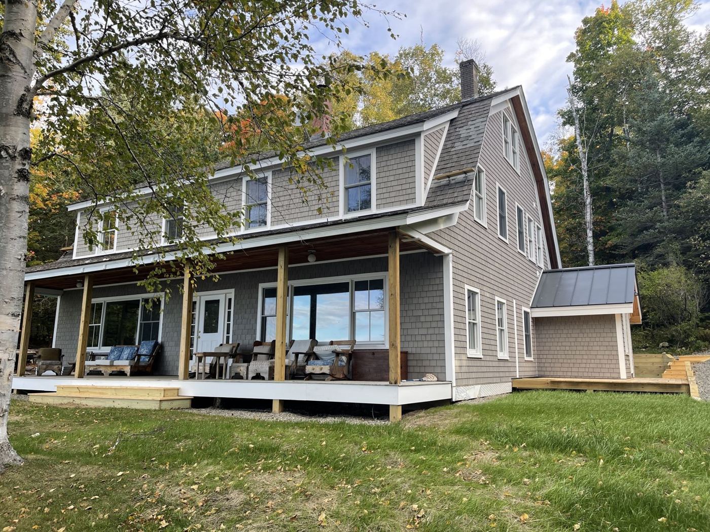 Shingled lake house with a long covered porch