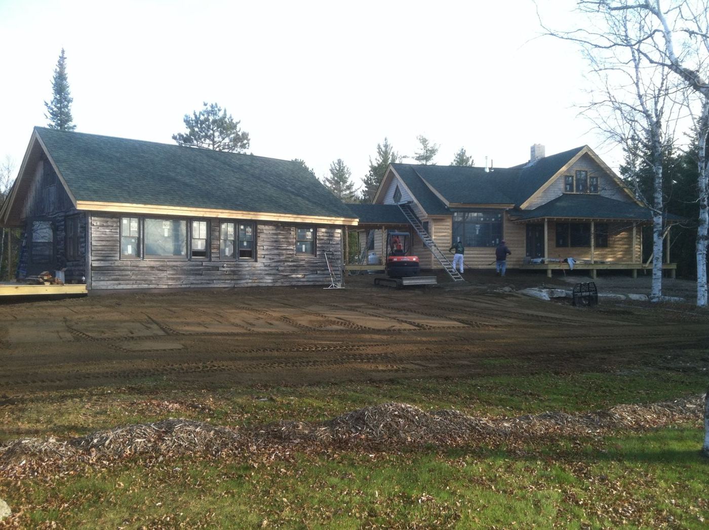 The restored log camp and the new log-sided home side by side during final grading