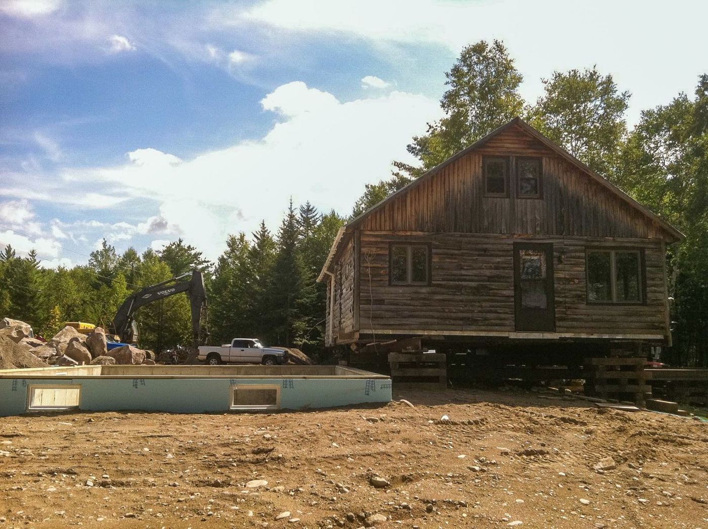 The original log camp lifted on cribbing beside a new ICF foundation