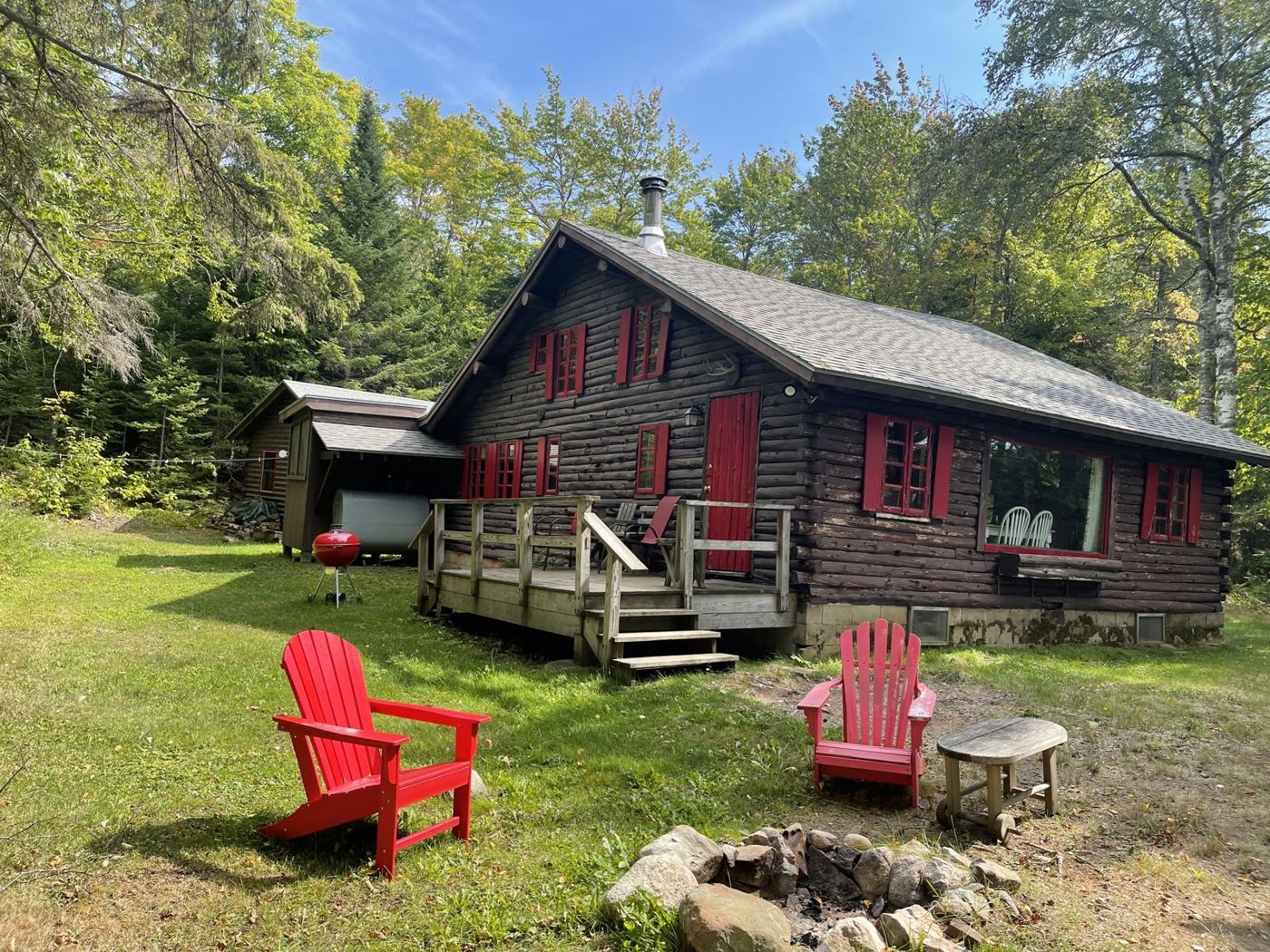 The original log cabin with red shutters and Adirondack chairs