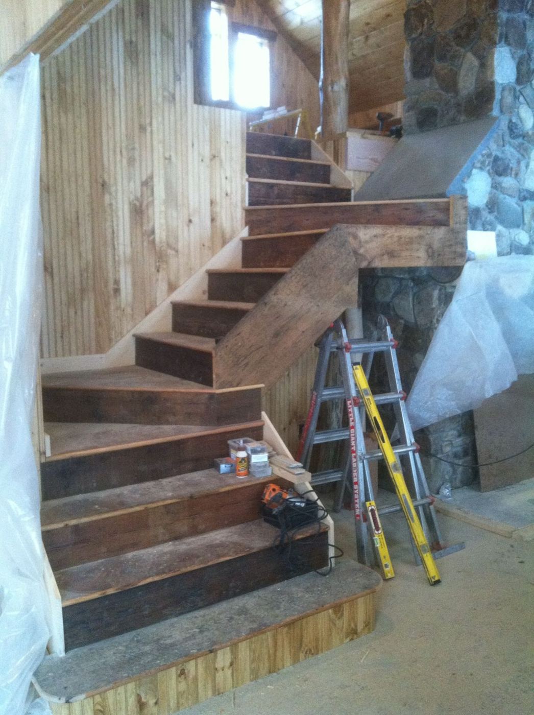Reclaimed wood staircase being built beside the stone fireplace
