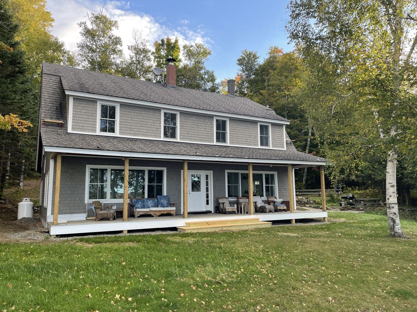 Shingled lake house with a long covered front porch