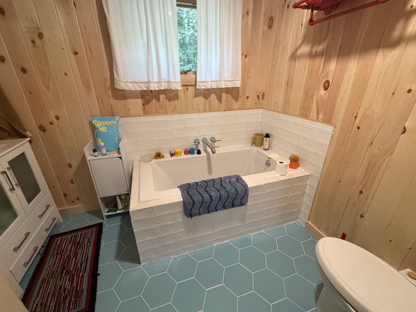 Tiled soaking tub with wall-mounted faucet, pine walls and blue hex floor tile