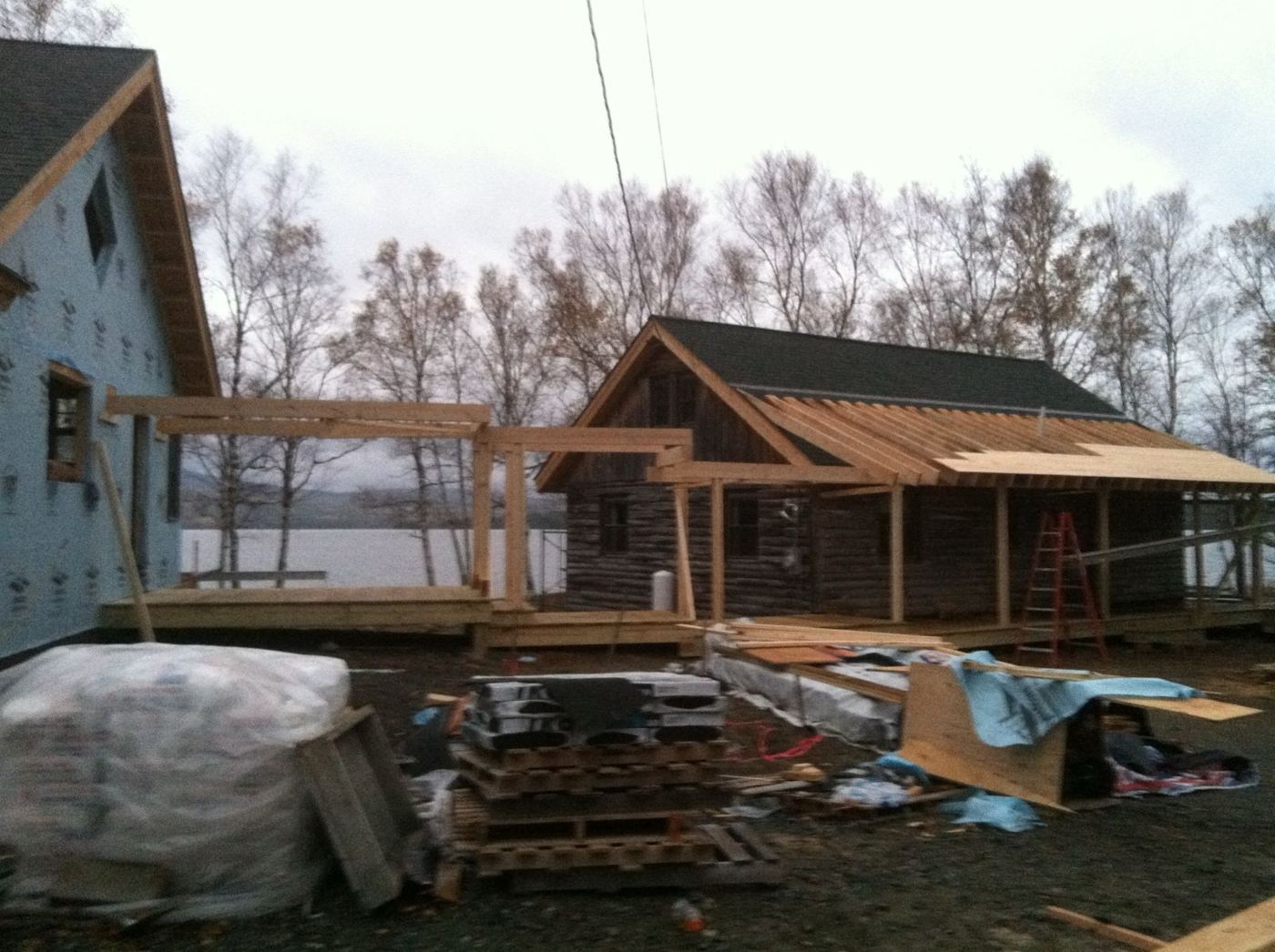 Timber porch framing connecting the new house to the log camp, with the lake beyond