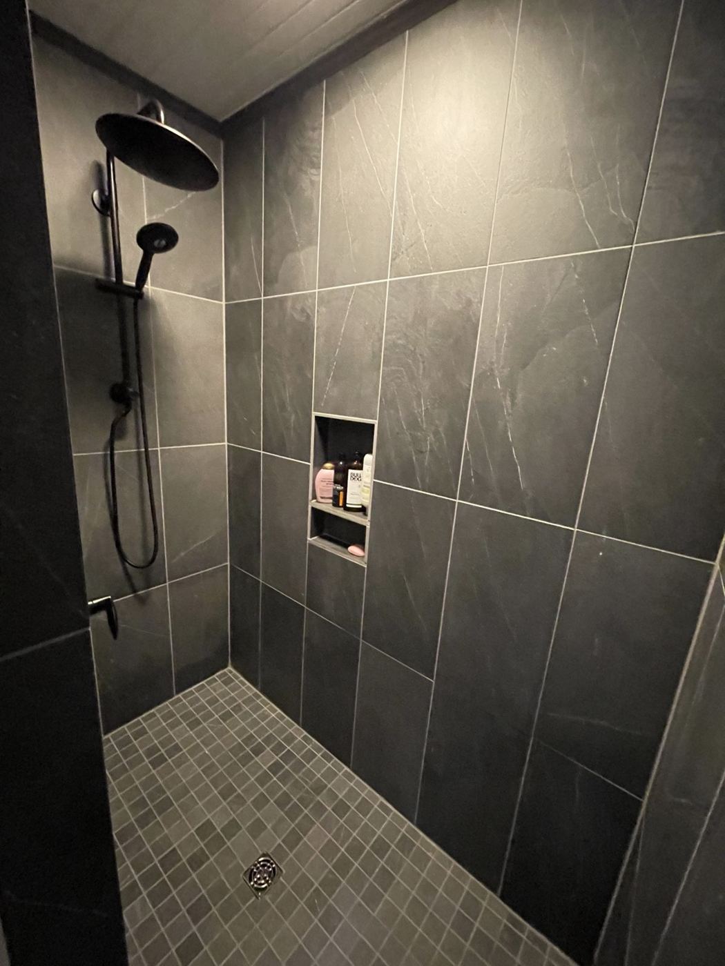 Walk-in shower with dark slate-look tile, rain head and built-in niche