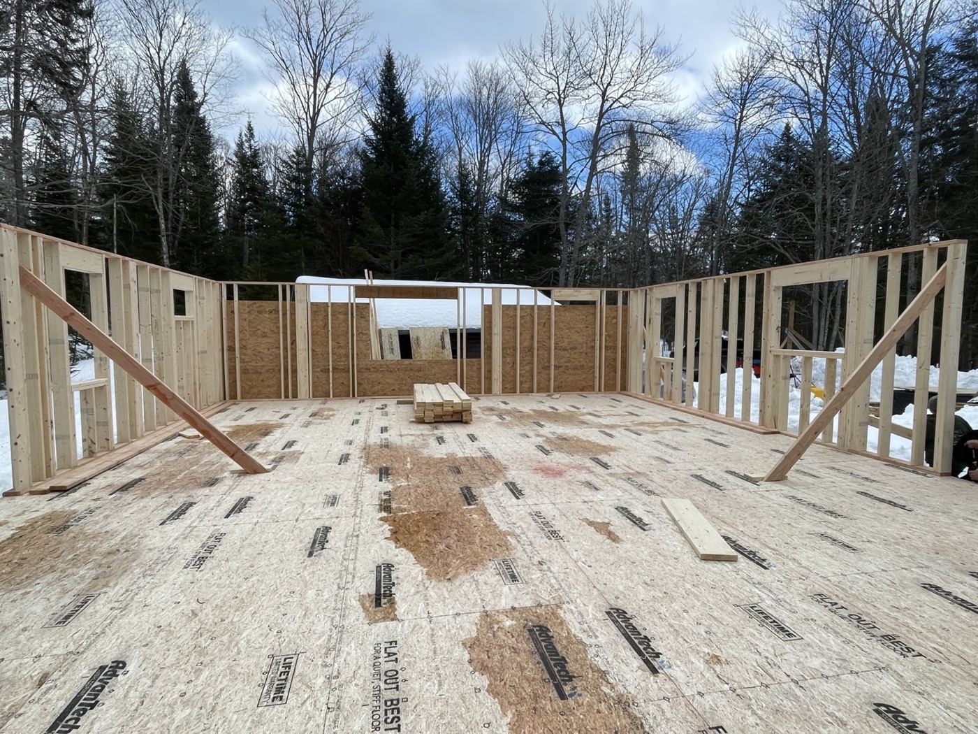First-floor walls framed on the new deck with snow on the ground